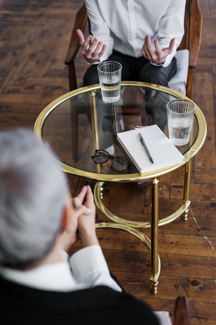 Mastering the First Impression: Your intriguing post title goes here Two adults discussing mental health in a counseling session across a glass table indoors.